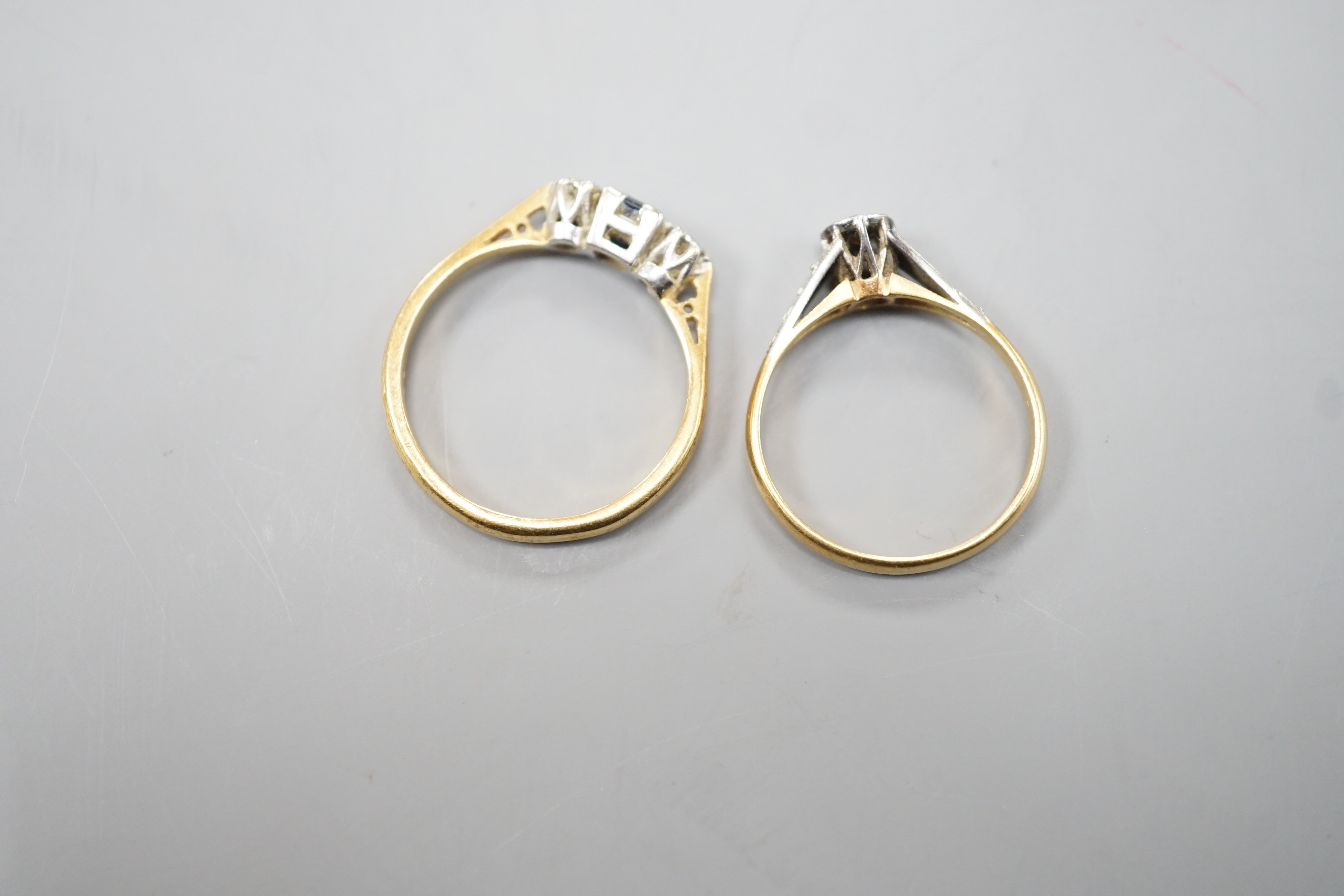 An 18ct, plat and illusion set solitaire diamond ring, size K/L and a modern 18ct gold, sapphire and diamond chip set three stone ring, size O, gross weight 4.8 grams.